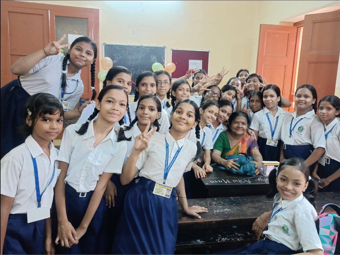 A classroom of students gathered around their teacher during a celebration.