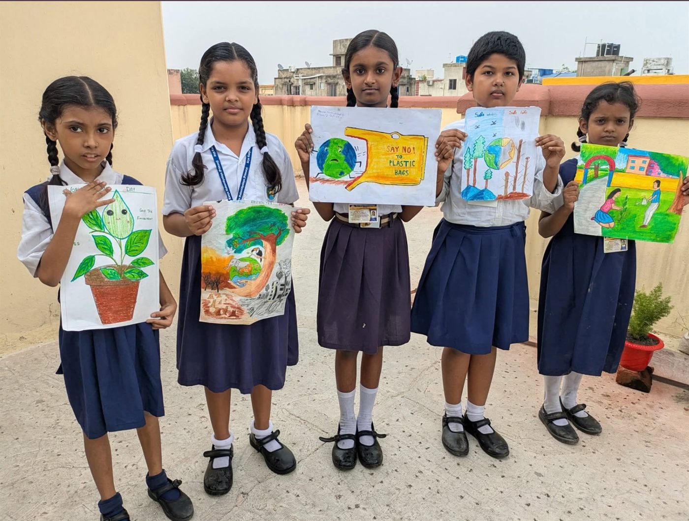 Five students holding hand-drawn posters for World Environment Day.